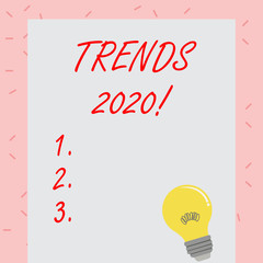 Text sign showing Trends 2020. Business photo showcasing general direction in which something is developing or changing Incandescent Light Bulb with Filament Inside Resting on Blank Color Paper
