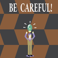 Writing note showing Be Careful. Business concept for making sure of avoiding potential danger mishap or harm Businessman Raising Arms Upward with Lighted Bulb icon above