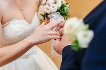 Obraz na płótnie Canvas the groom puts the ring on the bride's finger