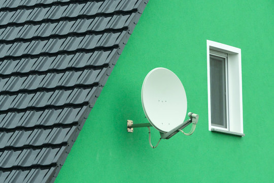 Satellitensch&uuml;ssel an einer gr&uuml;nen Gibelwand