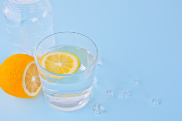 water with lemon on the blue background. Copy space.
