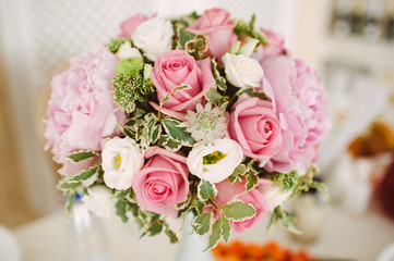 bouquet of peonies and roses in a vase on a served table