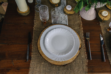 wooden table set with candles, glasses and plates