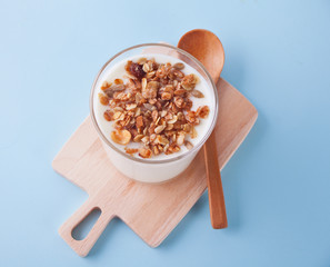 Granola with yogurt in glass on a blue table. Top view.