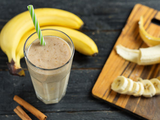 Banana smoothie with cinnamon in glass on wooden background