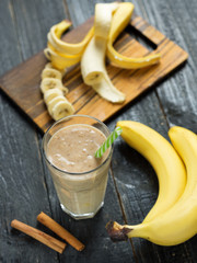 Banana smoothie with cinnamon in glass on wooden background