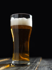 A glass of lager light beer on a dark wooden background