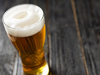 A glass of lager light beer on a dark wooden background