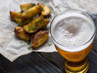 Country potatoes and beer in glass on wooden background