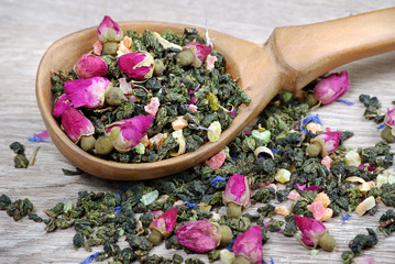 green tea. green tea with flowers in a wooden spoon. green tea with flowers and fruit pieces. blend tea