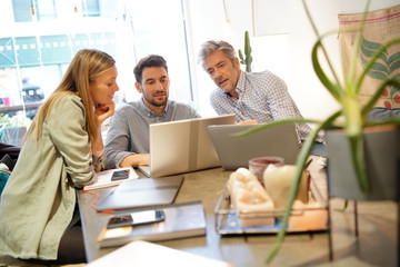 Colleagues looking at computer in coworking space