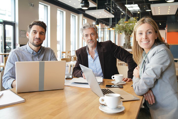 Sales team smiling at camera during breakfast meeting