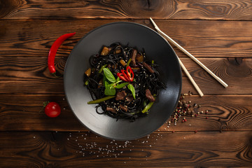 black noodle with marbled beef in a black plate on a wooden background