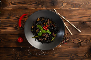 black noodle with marbled beef in a black plate on a wooden background