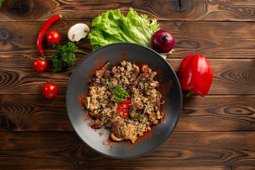 spicy fried rice with lamb in black plate on wooden background