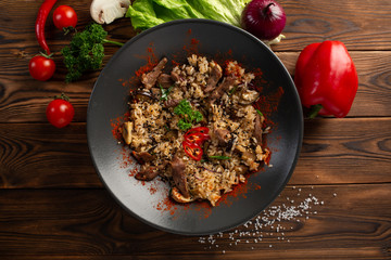spicy fried rice with lamb in black plate on wooden background