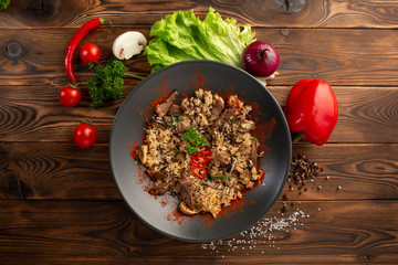 spicy fried rice with lamb in black plate on wooden background