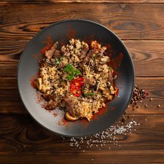 spicy fried rice with lamb in black plate on wooden background