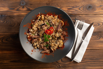 spicy fried rice with lamb in black plate on wooden background
