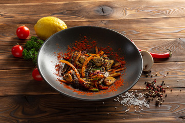 wok vegetables in a black plate on a wooden background