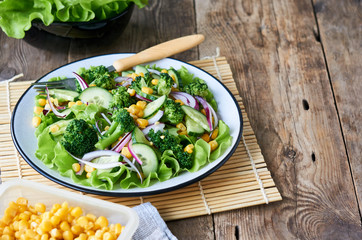 Vegetable salad with broccoli, corn and cucumbers on a plate