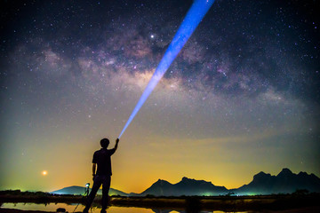 The man Shining the torch to milky way / Milky way with lighting