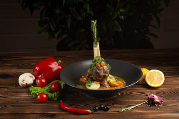 baked lamb shank with oriental herbs with vegetables on wooden background © Said Ramazanov