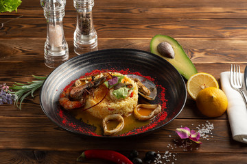 baked squid rings with rice and vegetables on a wooden background