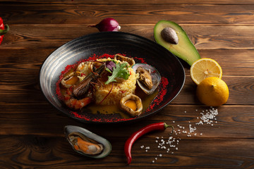 baked squid rings with rice and vegetables on a wooden background