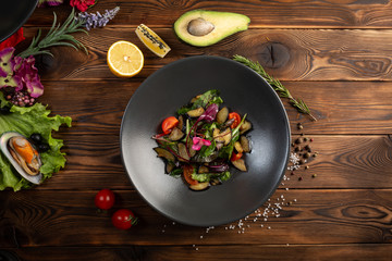 warm baked eggplant salad in a black plate on a wooden background