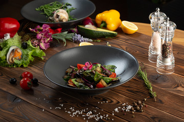 Fototapeta na wymiar warm baked eggplant salad in a black plate on a wooden background