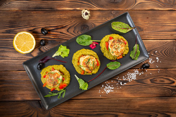 marine cutlets with mashed green peas in a black plate on a wooden background