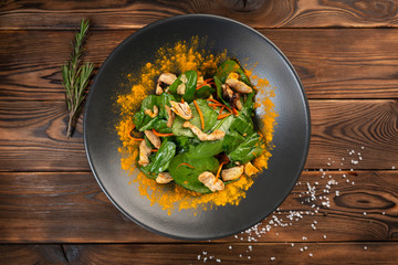 Chinese salad with chicken and sesame oil in a black plate on a wooden background
