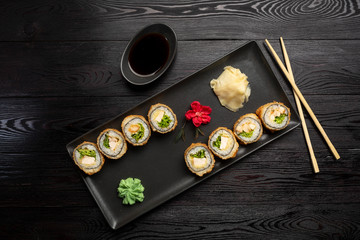 a set of rolls with cheese and herbs on a rectangular black plate on a black wooden background