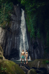 The guy and the girl at the waterfall. A pair of lovers. Bali trip. Tropics. Journey.
