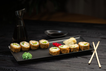 Fototapeta na wymiar a set of rolls with cheese and herbs on a rectangular black plate on a black wooden background