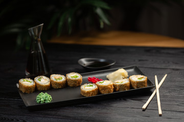 a set of rolls with cheese and herbs on a rectangular black plate on a black wooden background