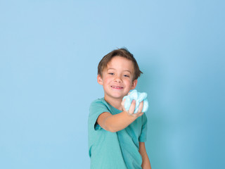 cool, pretty boy plays with homemade slime in front of a blue background and is having a lot of fun