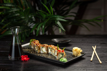 set dragon rolls on a rectangular black plate on a black wooden background