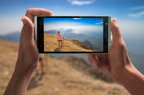 Girl hiker in a mountain valley on a screen of smartphone