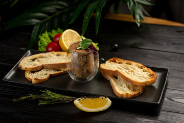 Japanese duck pate with warm ciabatta on a black plate on a black wooden background