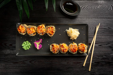 set of sushi rolls on a black rectangular plate on a black wooden background