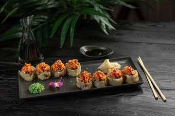 set of sushi rolls on a black rectangular plate on a black wooden background