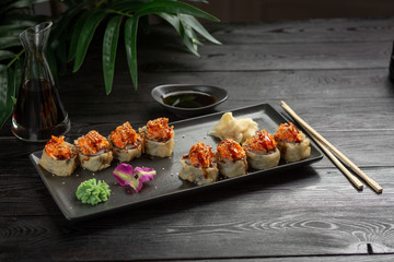 set of sushi rolls on a black rectangular plate on a black wooden background