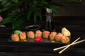 set of sushi rolls on a black rectangular plate on a black wooden background