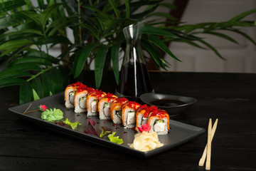 set of sushi rolls on a black rectangular plate on a black wooden background