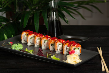 set of sushi rolls on a black rectangular plate on a black wooden background