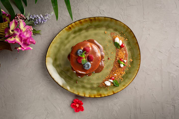 pancake with melted chocolate and berries on a green plate