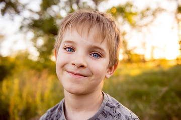 Smiling boy preschooler. Portrait of a boy in a sunset background. Summer portrait of child. 