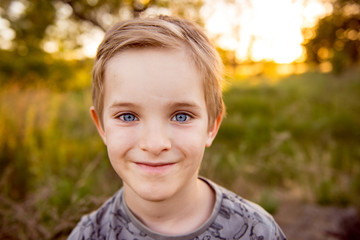 Smiling boy preschooler. Portrait of a boy in a sunset background. Summer portrait of child. 